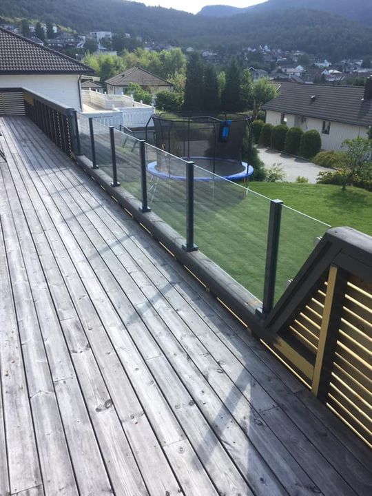 Glassrekkverk på mørkbeiset veranda