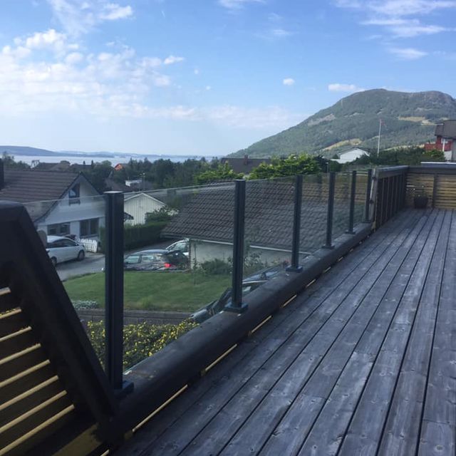 Mørkbeiset veranda med glassrekkverk