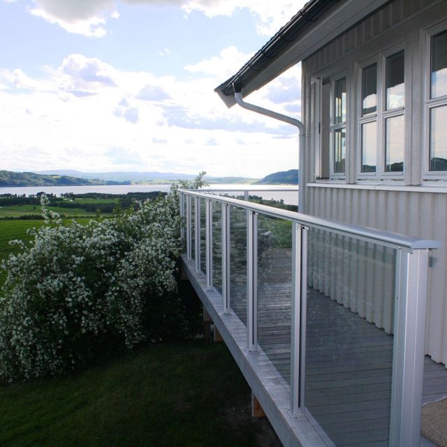Grå bolig med glassrekkverk på veranda